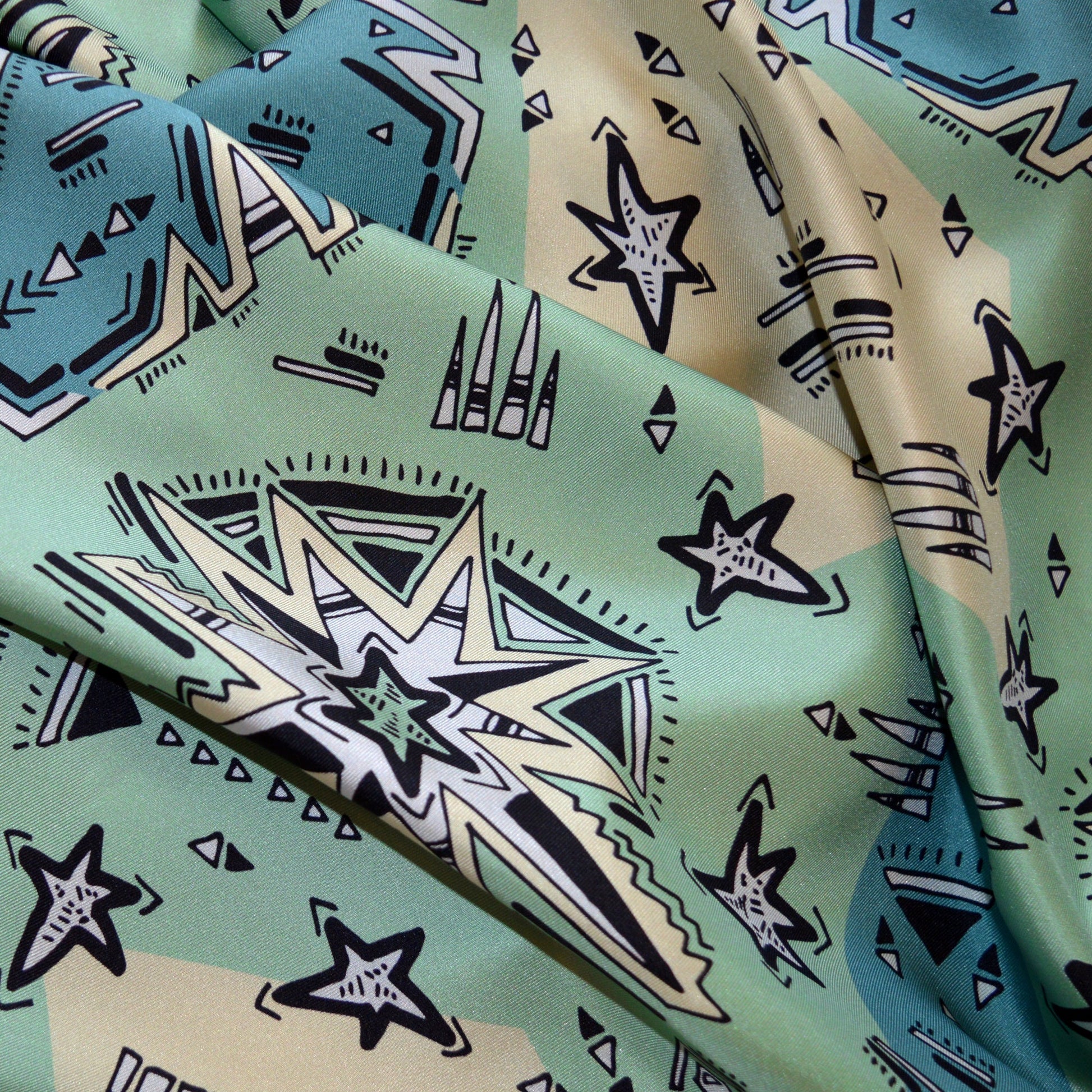 particolare di tessuto 100% seta Made in Italy stampata con disegno creativo dal tratto nero e base chiara