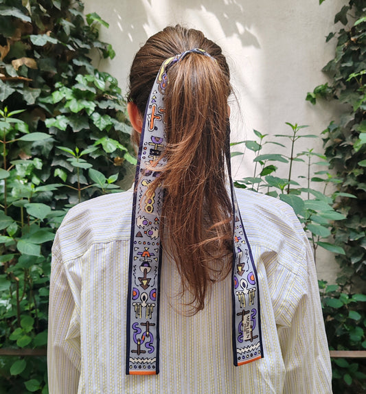 foto di modella di schiena con twilly di seta stampata legato con una coda tra i capelli con sfondo giardino