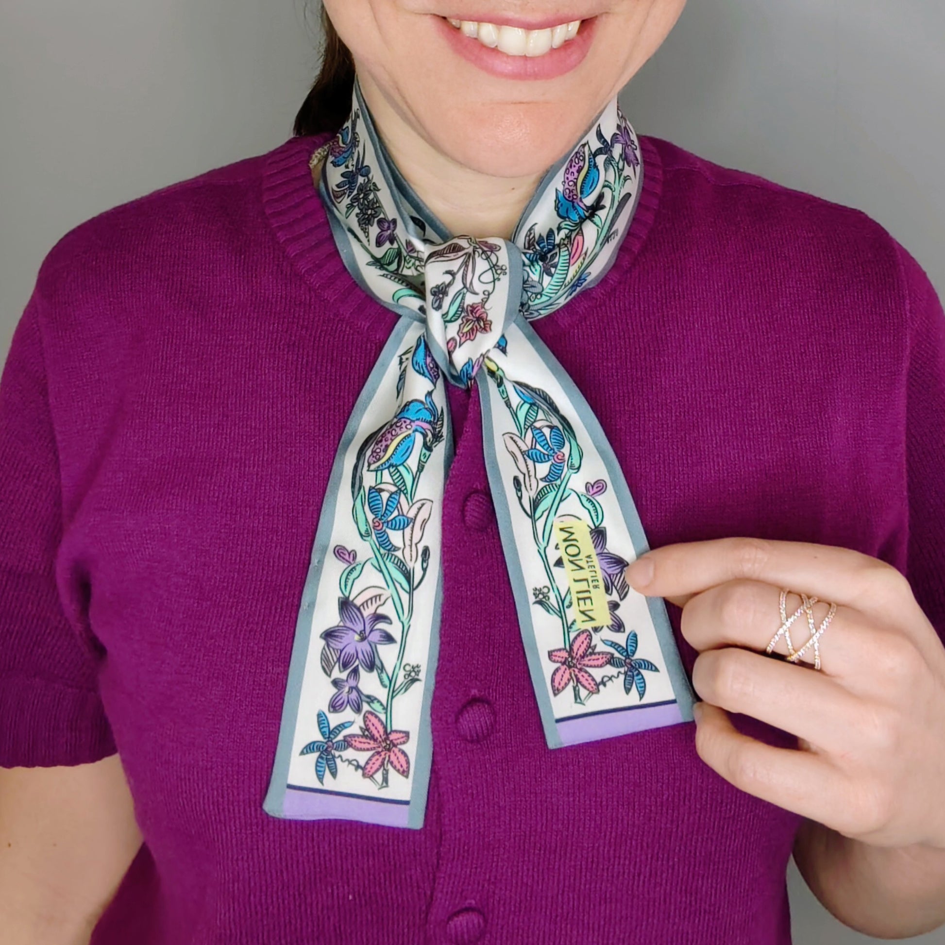 modella indossa twilly in seta annodato al collo del cardigan con stampa fiori multicolore