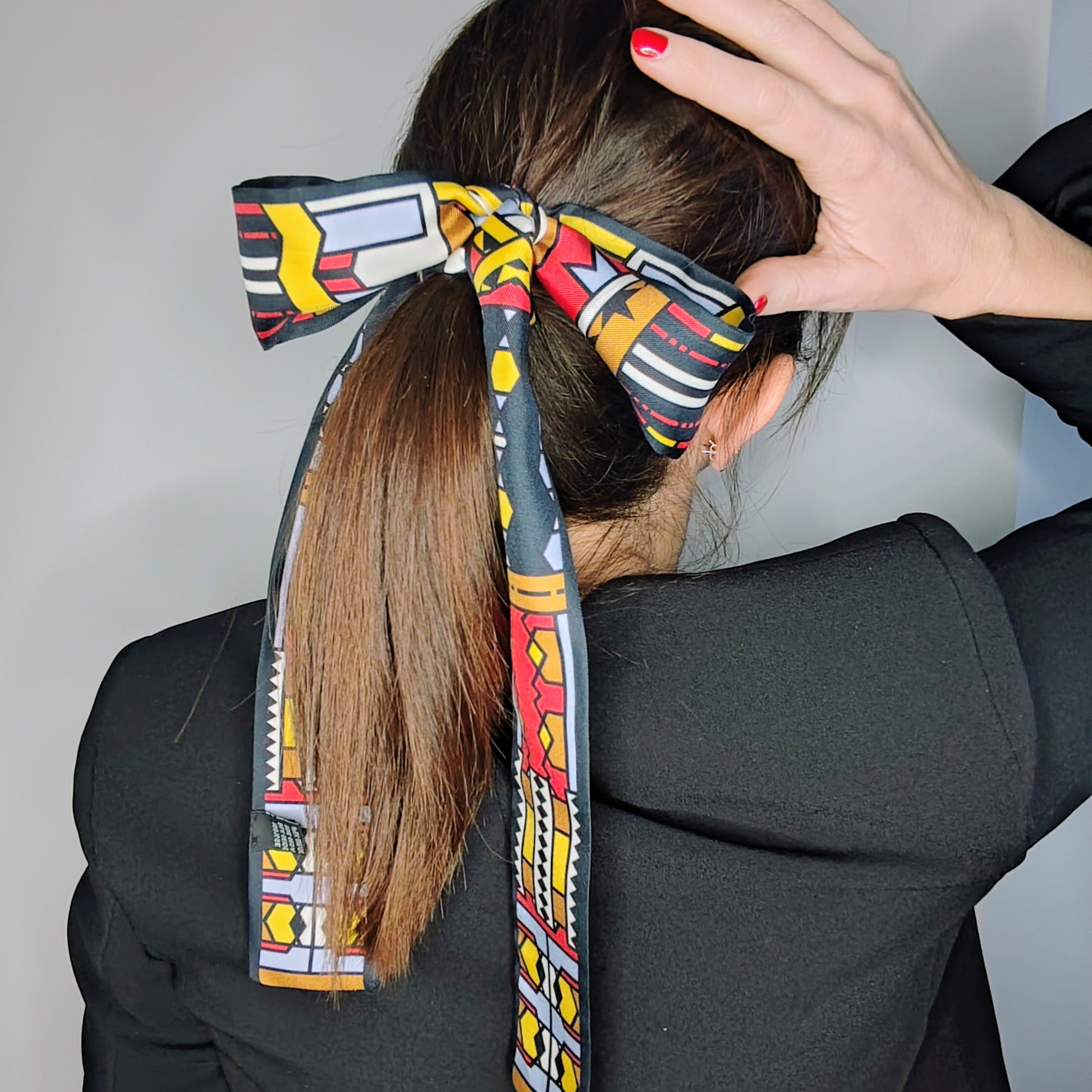 twilly stampata in seta rossa oro indossata con un fiocco come coda di cavallo tra i capelli