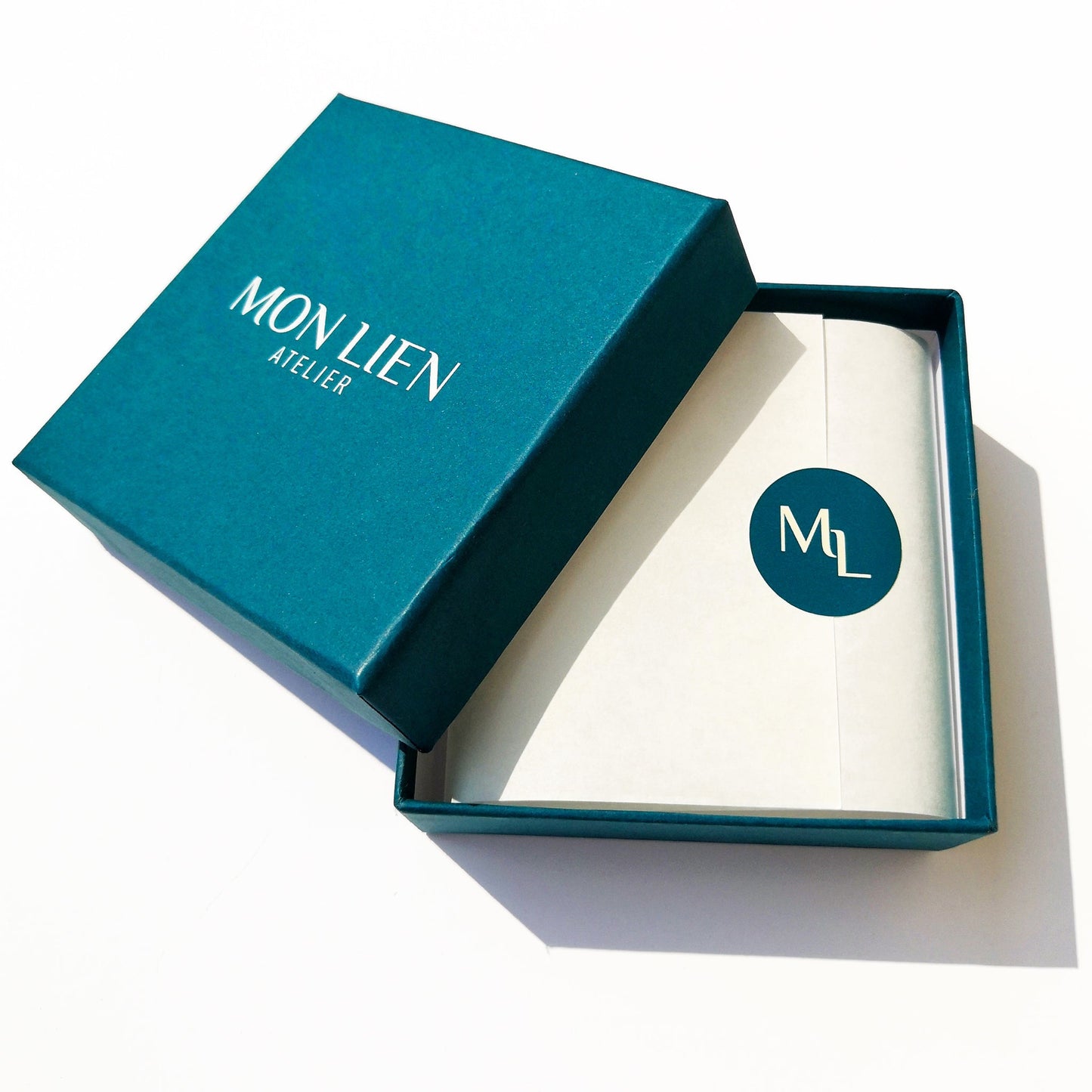 packaging di scatola con coperchio logo mon lien atelier biglietto del marchio e sticker carta velina con simbolo colore ottanio e avorio