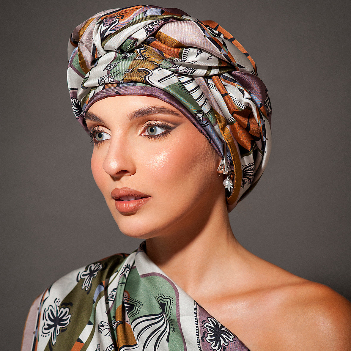 stupenda modella con viso in primo piano vestita da un accessorio di seta e da un turbante annodato in testa dai colori naturali avorio e terra