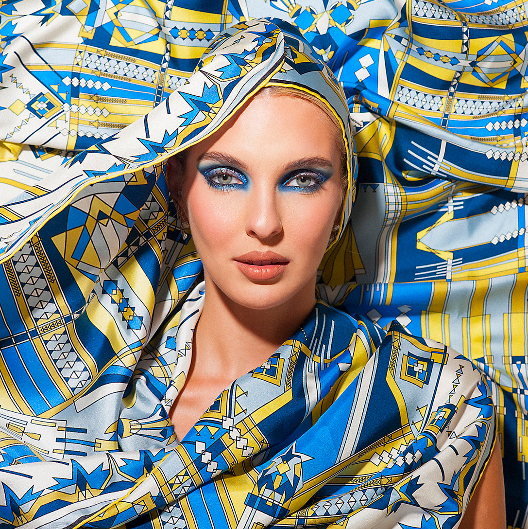 viso di modella drappeggiata da foulard e stola blu e gialla