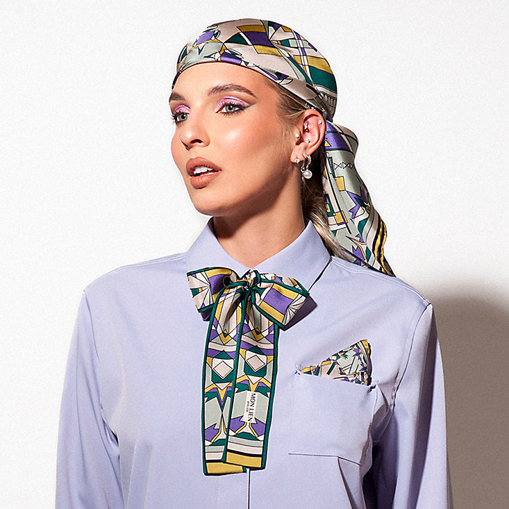modella in posa con fusciacca annodata al collo della camicia pochette nel taschino e foulard bandana in testa dai colori viola e verde