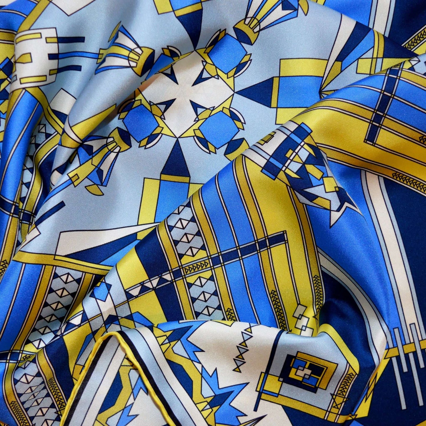 vista ingrandita di un particolare di foulard su tessuto in seta con motivi blu giallo avorio