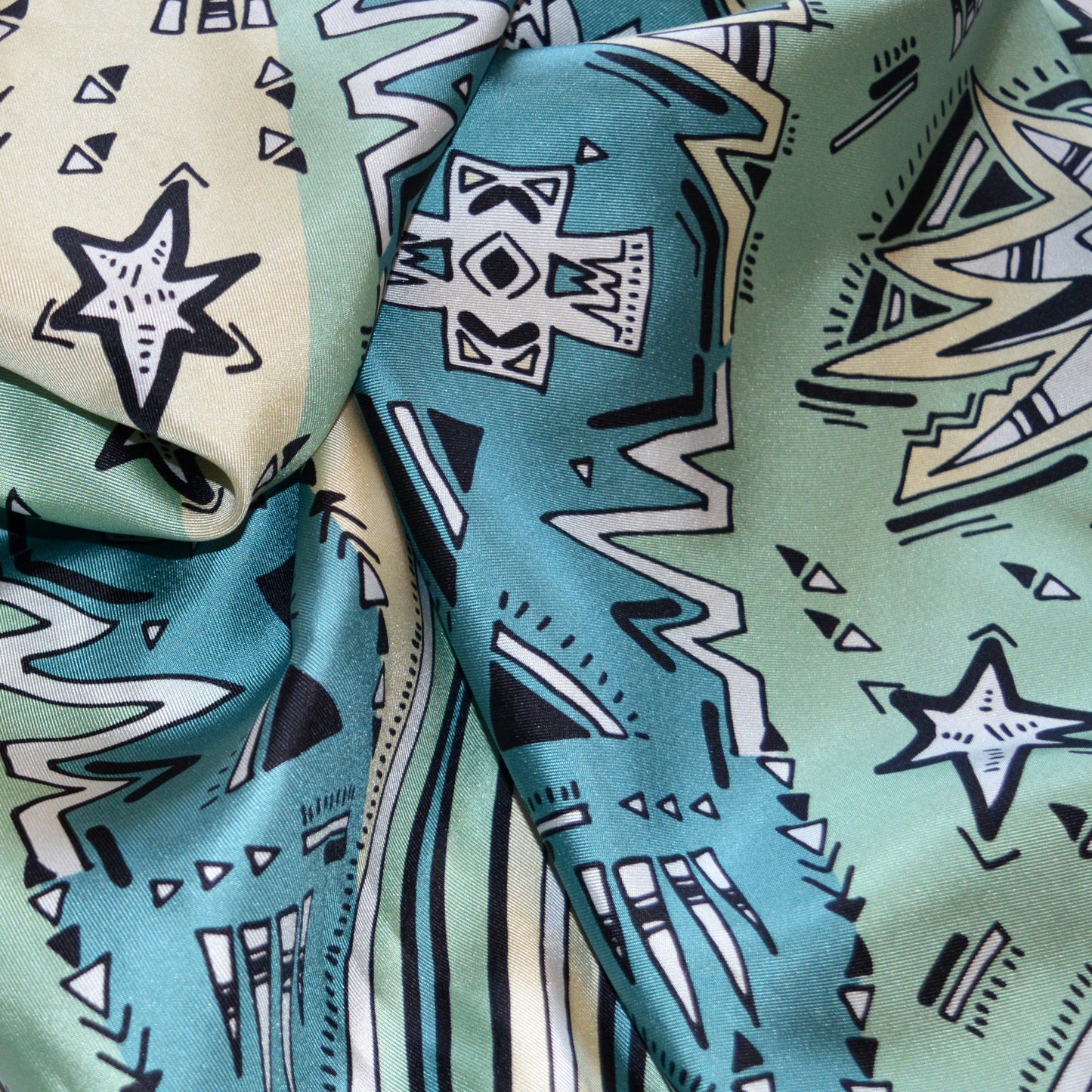 particolare di foulard pregiato con motivi grafici di stelle e righe in palette turchese ottanio avorio beige