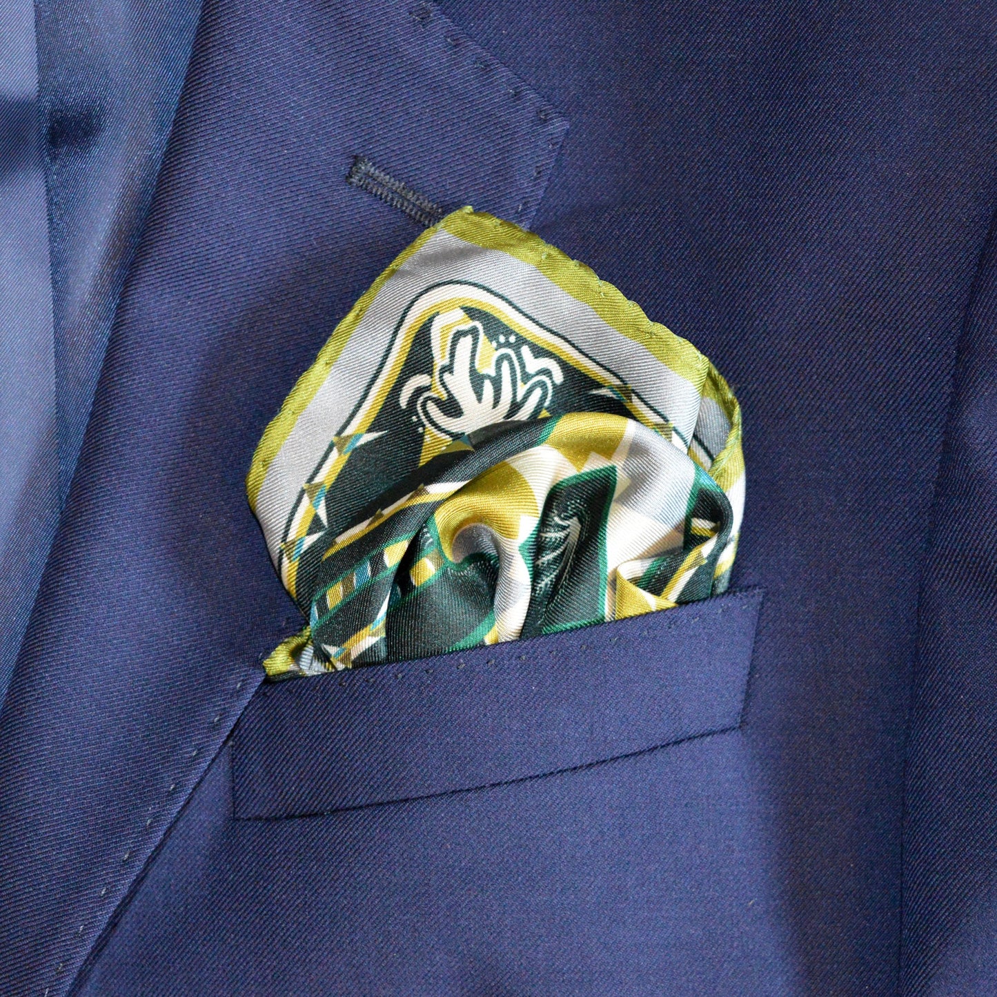 elegante fazzoletto da taschino in seta piegato e inserito nella tasca della giacca con disegno in palette verde e ocra